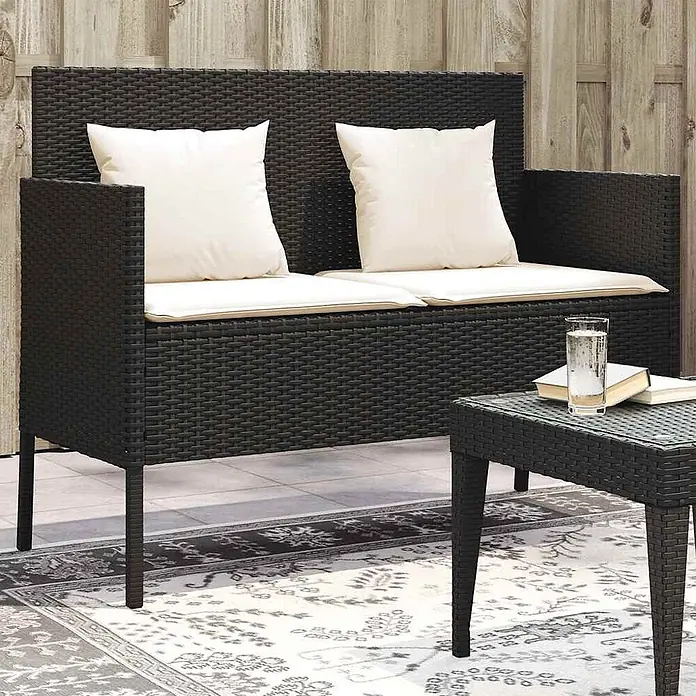Furnicato Gartenbank PE-Rattan - B x T x H: 113 x 61 x 87 cm, Schwarz und Creme - Dunkelbraunes Outdoor-Sitzset aus Geflecht mit weißen Kissen und einem Beistelltisch mit Glasplatte.