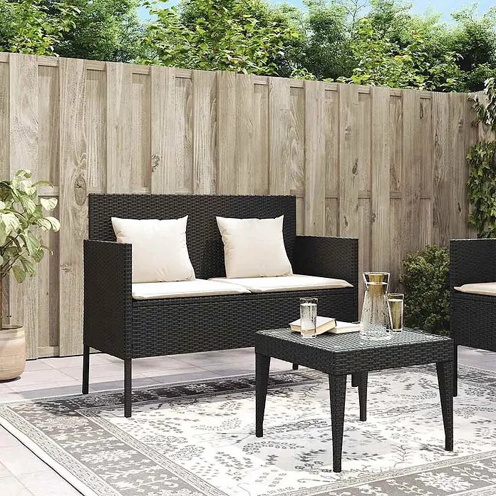 Furnicato Gartenbank PE-Rattan - B x T x H: 113 x 61 x 87 cm, Schwarz und Creme - Schwarzes Rattan-Gartensofa und quadratischer Couchtisch mit cremefarbenen Kissen auf einem Outdoorteppich.