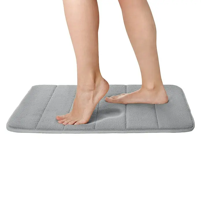 Tatay Alfombra de baño Nuvola - 60 x 40 cm, Poliéster, Gris - Una alfombrilla de baño de espuma viscoelástica gris con una persona pisándola, demostrando su suavidad y comodidad.