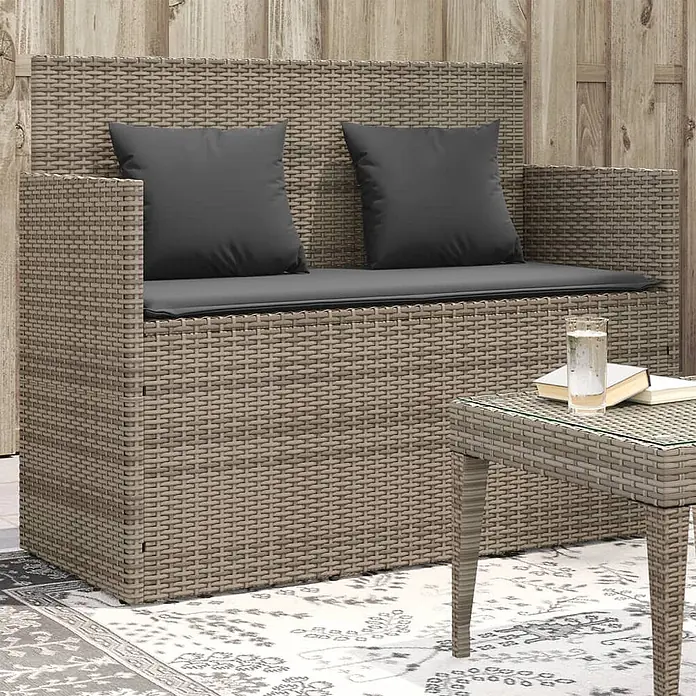 Furnicato Gartenbank PE-Rattan - B x T x H: 120 x 50 x 90,5 cm, Grau - Helles, geflochtenes Rattan-Gartensofa mit dunkelgrauen Kissen und passendem Beistelltisch mit Glasplatte auf einer Terrasse.