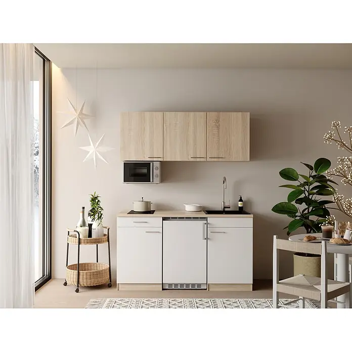 Respekta Miniküche Ingrid - Breite: 150 cm, Weiß, Mit Kochfeld + Kühlschrank + Mikrowelle - Kompakte Küchenzeile mit hellen Holz-Oberschränken und weißen Unterschränken, integrierter Mikrowelle, Kochfeld und Spüle, in einem hellen Wohnraum.