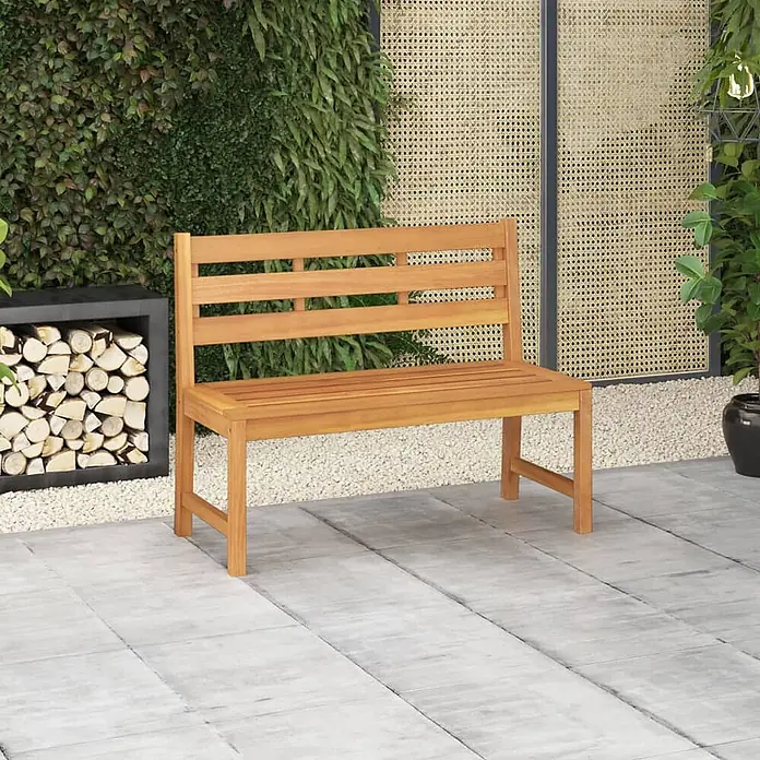 Furnicato Gartenbank Teak-Hartholz - B x T x H: 114 x 59 x 90 cm, Braun - Hellbraune Gartenbank aus Holz auf einer Außenterrasse mit Grünpflanzen und gestapeltem Brennholz.