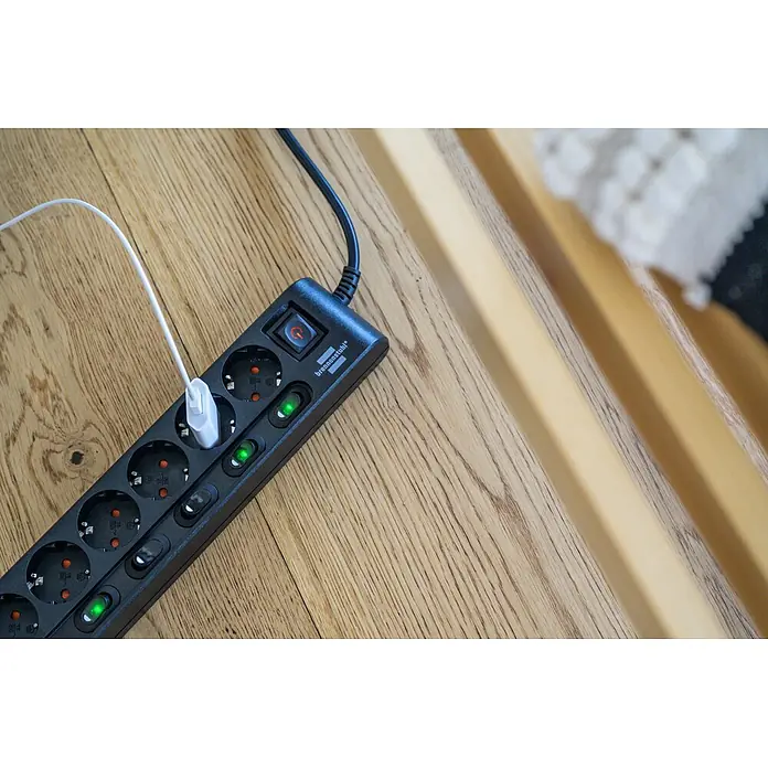 Brennenstuhl Steckdosenleiste einzeln schaltbar - 6-fach, Schwarz, Kabellänge: 2 m, IP20, Mit Schalter - Schwarze Brennenstuhl Steckdosenleiste mit mehreren Buchsen und Einzelschaltern, ein weißes Kabel ist eingesteckt, auf Holz.