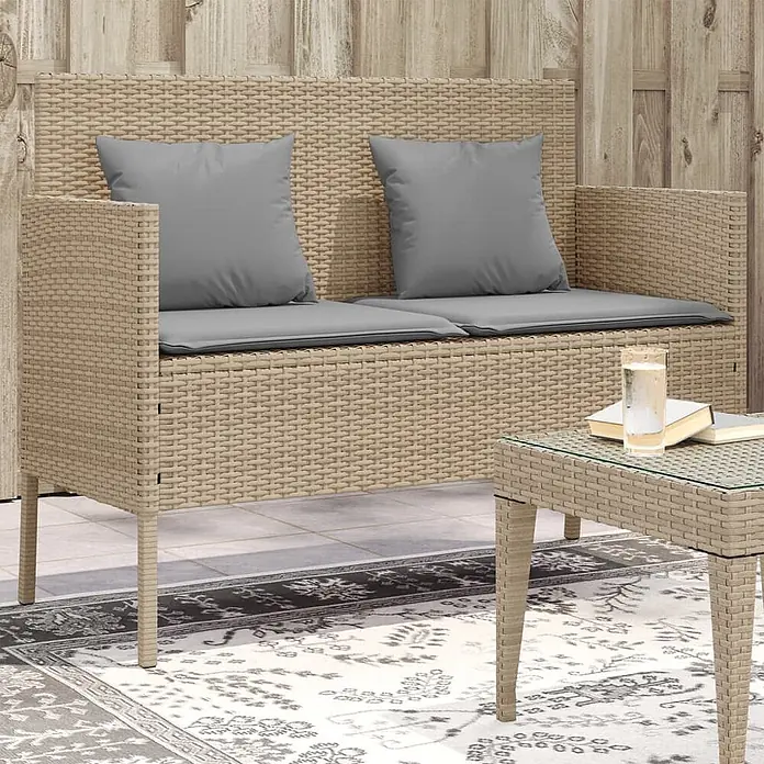 Furnicato Gartenbank PE-Rattan - B x T x H: 113 x 61 x 87 cm, Beige und Grau - Beigefarbenes Rattan-Outdoor-Sofa mit grauen Kissen und passendem Couchtisch auf einer Terrasse.