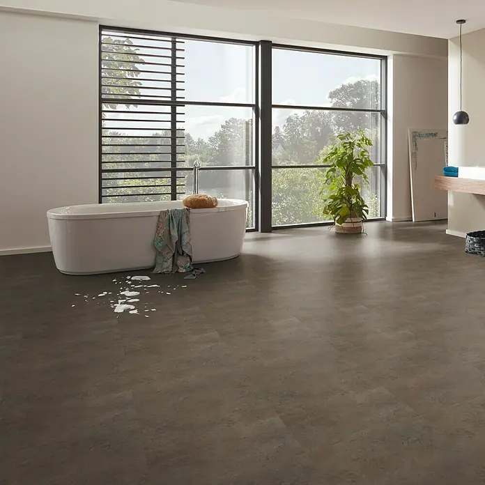 Vinylboden Isocore Inside - Umbria, Fliese, 600 x 600 x 8 mm - Ein modernes Badezimmer mit braunem Bodenbelag, einer freistehenden Badewanne und einem großen Fenster mit Blick auf die Natur.