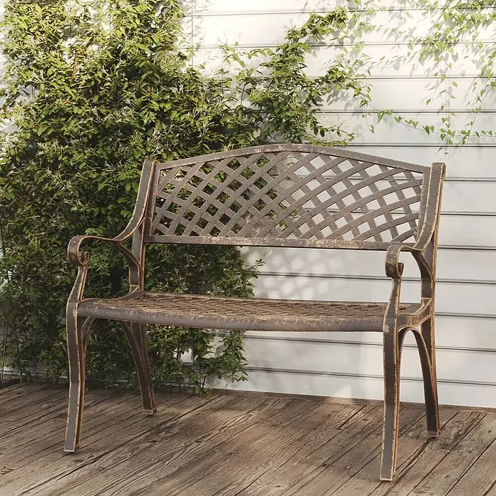 Furnicato Gartenbank - Bronzefarben - Dunkelbronzefarbene Metallgartenbank mit Gitterlehne und geschwungenen Armlehnen auf einer Holzterrasse.