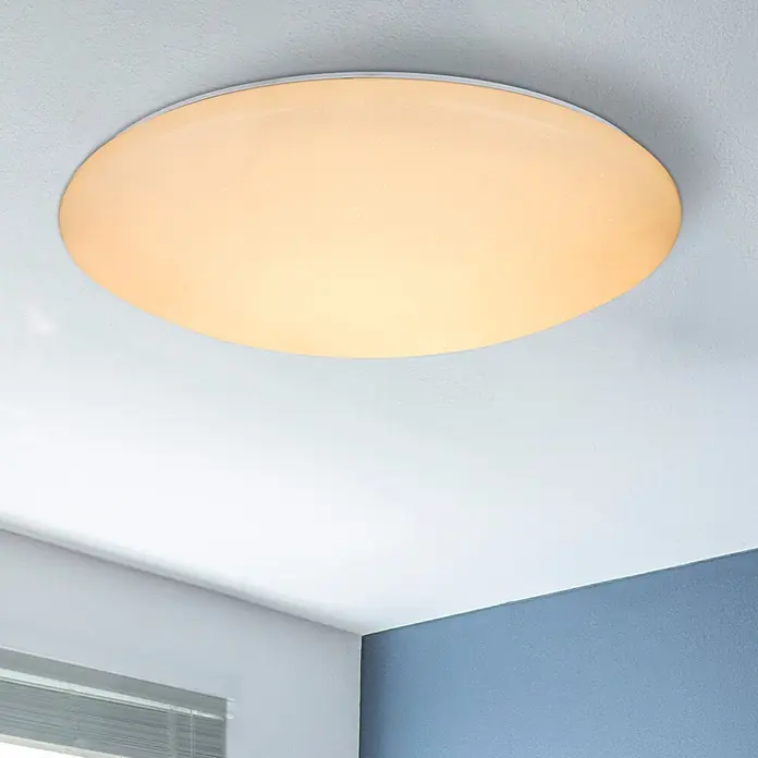 Globo LED-Deckenleuchte Atreju - 48 W, Weiß, RGB - Runde LED-Deckenleuchte mit weißem Rahmen und mattierter Abdeckung, warmes Licht spendend, über einer Zimmerecke montiert.