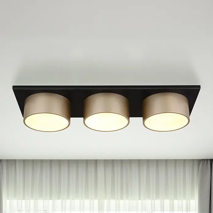 Globo Deckenleuchte Raymond - 24 W, L x B x H: 580 x 200 x 110 mm, Lichtfarbe: Warmweiß - Schwarze rechteckige Deckenleuchte mit drei zylinderförmigen champagnerfarbenen Leuchten, die warmes Licht abstrahlen.