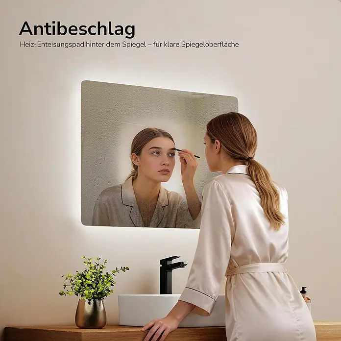 Emke Lichtspiegel Glowrim LM09 -  - Beleuchteter Anti-Beschlag-Badezimmerspiegel, der eine klare Reflexion einer Frau beim Schminken in einer dampfigen Umgebung zeigt.