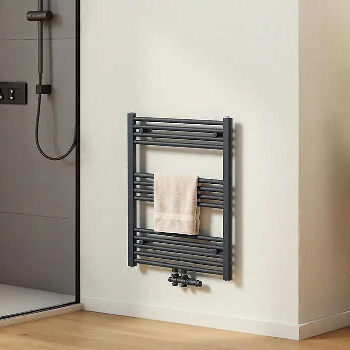 Emke Badheizkörper Orbrad TR - B x H: 60 x 75 cm, Anthrazit - Dunkelgrauer Handtuchheizkörper mit beigem Handtuch an der Badezimmerwand neben einer Dusche.