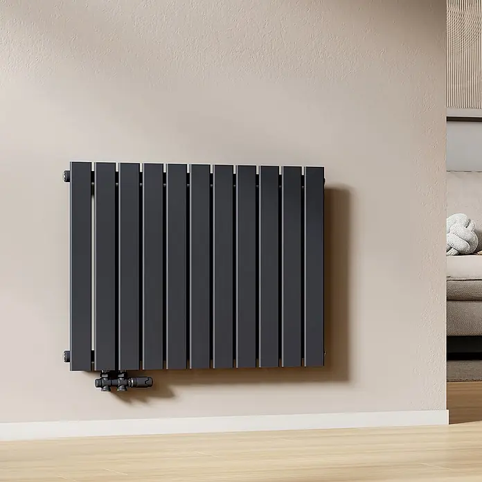 Emke Designheizkörper Flatrad FR - Wärmeleistung bei Vorlauftemperatur von 75 °C (D: 50): 618 W, Anthrazit - Dunkelgrauer Flachheizkörper an heller Wand mit Holzfußboden, Heizungsventile sichtbar. Im modernen Wohnraum.
