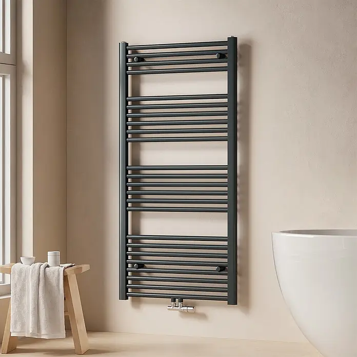 Emke Badheizkörper Rundrohr Thermio TR - B x H: 60 x 120 cm, Anthrazit - Dunkelgrauer Handtuchheizkörper an einer hellbeigen Badezimmerwand, neben einem Fenster und einer weißen Badewanne.
