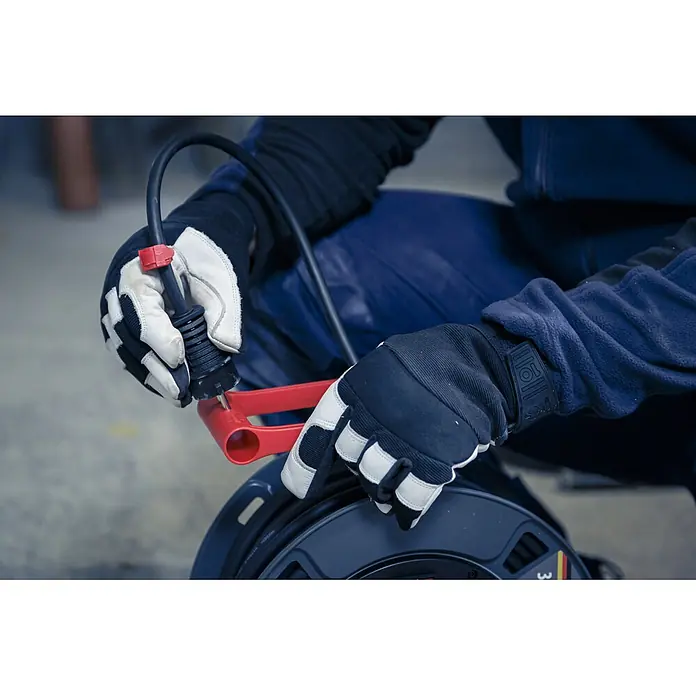 Brennenstuhl Kabeltrommel 300 KU 4100 - Kunststoff, 40 m, H07RN-F, IP44 - Person in Handschuhen wickelt schwarzes Kabel auf dunkle Kabeltrommel mit rotem Kurbelgriff.