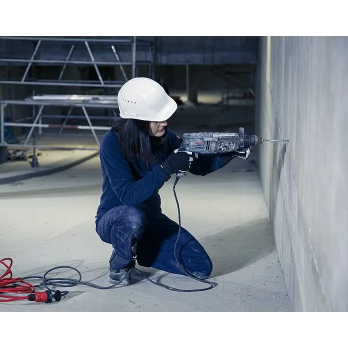 Brennenstuhl Verlängerungskabel BREMAXX-PUR - 25 mm, Rot, IP44, H07BQ - Arbeiter bohrt mit einem grauen Bosch Bohrhammer in eine Betonwand.