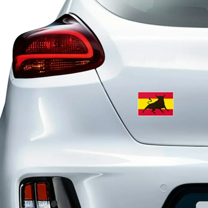 Etiqueta adhesiva Toro España - Bandera - Adhesivo con el símbolo del toro de Osborne español adherido a la parte trasera de un coche blanco, un homenaje a España.