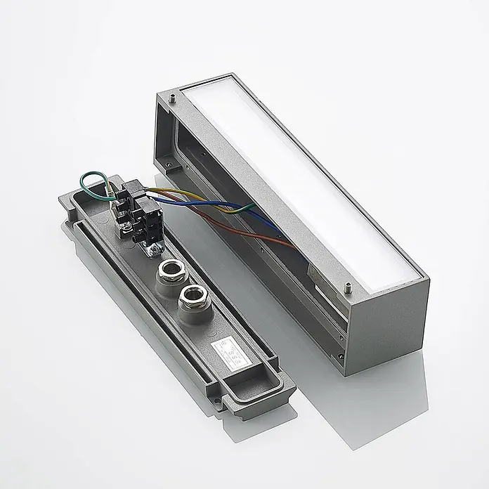 Arcchio Außenwandleuchte Lengo - alu / grau / zink, IP65 - Offene graue rechteckige LED-Wandleuchte, zeigt Innenverdrahtung, Klemmblock und Kabelverschraubungen zum Elektroanschluss.
