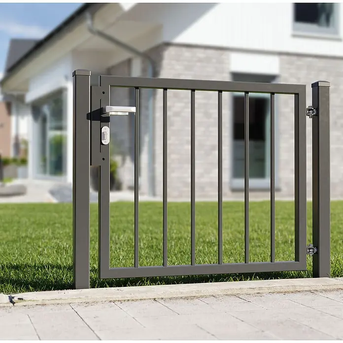 Deutsche Zauntechnik Zauntor Vario Basic - 100 x 180 cm, Anthrazitgrau, Stahl - Anthrazitfarbenes Metall-Gartentor mit Griff und Schloss, im Freien vor einem unscharfen Haus installiert.
