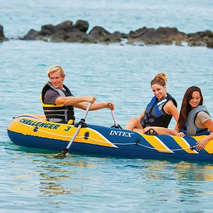Intex Bote hinchable Challenger 3 - 2,95 x 1,37 m, Carga útil: 170 kg - Tres personas disfrutando de un paseo en el Intex Challenger 3 en el agua, todos con chalecos salvavidas.