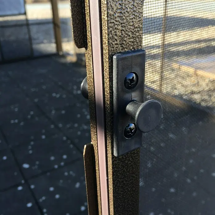 Sojag Standard-Pavillon Castel 12 x 14 - B x T: 427 x 362 cm, Farbe Gestell: Bronze, Aluminium - Nahaufnahme eines schwarzen Riegels an einer bronzefarbenen Tür, der Sicherheit und Funktionalität in den Vordergrund stellt.