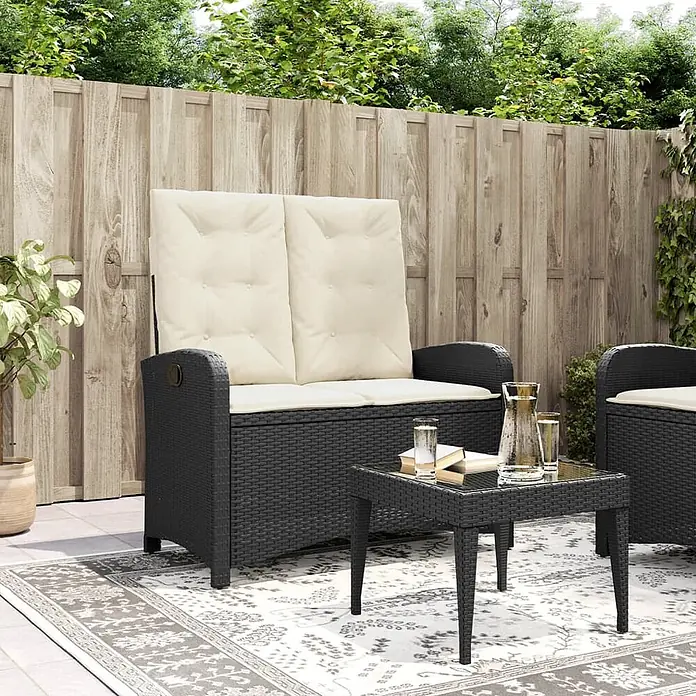Furnicato Gartenbank PE-Rattan - B x T x H: 105 x 86 x 83 cm, Schwarz und Creme - Schwarze Rattan-Sitzbank mit Stauraum und cremefarbenen Kissen, passender Stuhl und Tisch auf einer Terrasse.