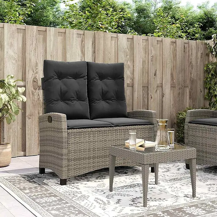 Furnicato Gartenbank - B x T x H: 66 x 90 x 93 cm, Grau - Graue Outdoor-Sitzbank im Rattan-Stil mit schwarzen Kissen und passendem Beistelltisch, auf einer Terrasse.