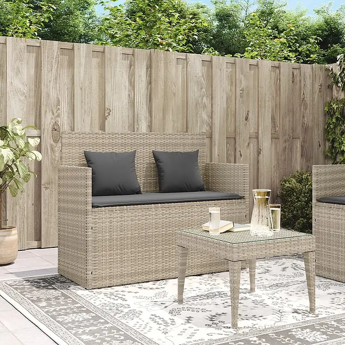 Furnicato Gartenbank - B x T x H: 110 x 50 x 90,5 cm, Hellgrau - Helle beige Rattan-Gartengarnitur mit dunklen Kissen und passendem Tisch, auf einem Terrassenteppich arrangiert.