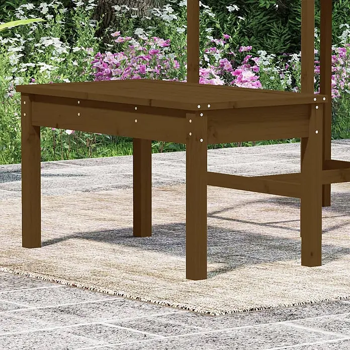 Furnicato Gartenbank Kiefer-Massivholz Honigbraun - B x T x H: 80 x 44 x 45 cm, Honigbraune Kiefer - Brauner Holztisch für den Außenbereich auf einem Terrassenteppich, umgeben von Gartenblumen.
