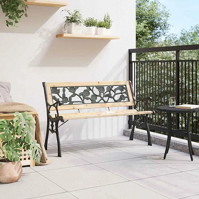 Furnicato Gartenbank Holz Anthrazit - B x T x H: 54 x 116 x 73 cm, Braun - Gartenbank für draußen mit schwarzem Metall-Rückenlehne im Rosenmuster und hellen Holzlatten auf einem Balkon.