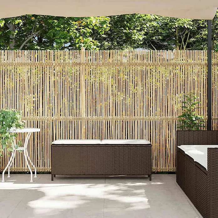 Furnicato Gartenbank PE-Rattan - B x T x H: 110 x 30 x 40,5 cm, Braun und Cremeweiß - Natürlicher Bambus-Sichtschutz, draußen hinter Gartenmöbeln installiert.