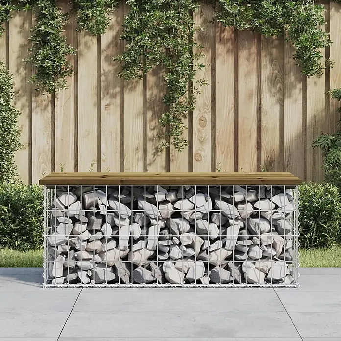 Furnicato Gartenbank Kiefernholz imprägniert - B x T x H: 103 x 44 x 42 cm, Imprägniertes Kiefernholz - Gabionenbank für den Außenbereich mit hellgrauen Steinen und Holzplatte, vor einem Gartenzaun.