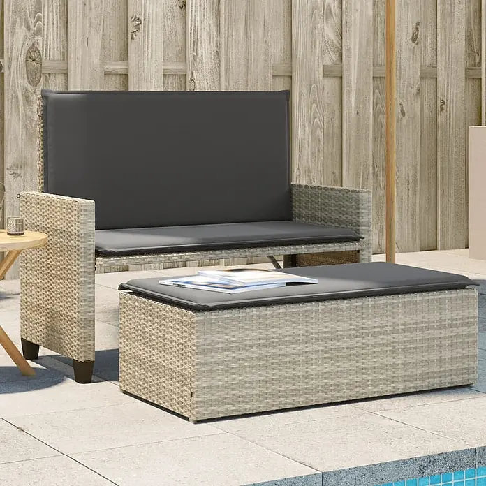 Furnicato Gartenbank PE-Rattan - B x T x H: 122 x 115 x 61,5 cm, Hellgrau - Hellgraues Polyrattan-Gartensofa mit dunkelgrauen Kissen und passendem Stauraum-Ottoman auf einer Terrasse.