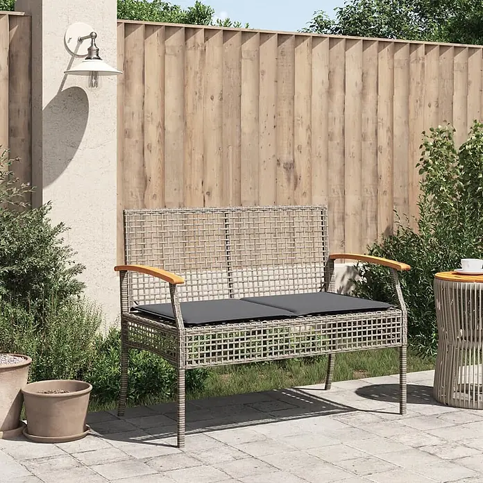Furnicato Gartenbank - Grau - Graue Outdoor-Bank im Rattan-Stil mit dunklen Kissen und Holzarmlehnen, auf einer Terrasse platziert.