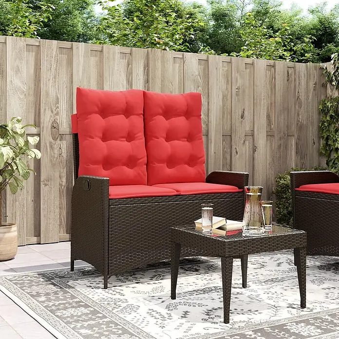 Furnicato Gartenbank PE-Rattan - B x T x H: 104 x 86 x 83 cm, Braun - Dunkelbraune Rattan-Garten-Aufbewahrungsbank mit roter Polsterung, auf einer Terrasse mit kleinem Tisch.