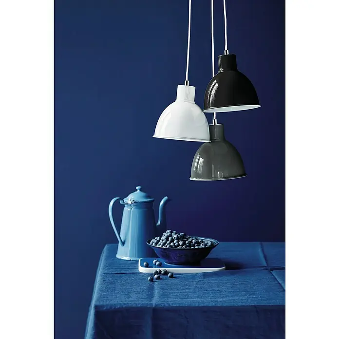 Nordlux Lámpara colgante redonda Pop - 60 W, Ø x Al: 21,5 x 23 cm, Negro, E27 - Tres lámparas colgantes en blanco, negro y gris cuelgan sobre una mesa con arándanos y una tetera azul.