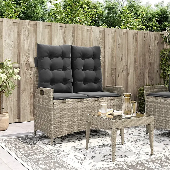 Furnicato Gartenbank - B x T x H: 59 x 86 x 93 cm, Hellgrau - Helles Rattan-Gartenlounge-Set mit Zweisitzer-Sitzbank mit Stauraum, dunklen Kissen und passendem Couchtisch auf einer Terrasse.