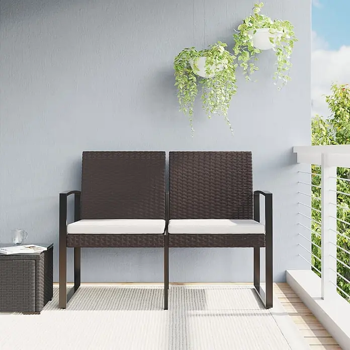 Furnicato Gartenbank PP-Rattan Anthrazit - B x T x H: 103,5 x 57 x 77,5 cm, Braun - Braune Rattan-Sitzbank für zwei Personen mit weißen Kissen und passendem Beistelltisch auf einem Balkon mit Hängepflanzen.