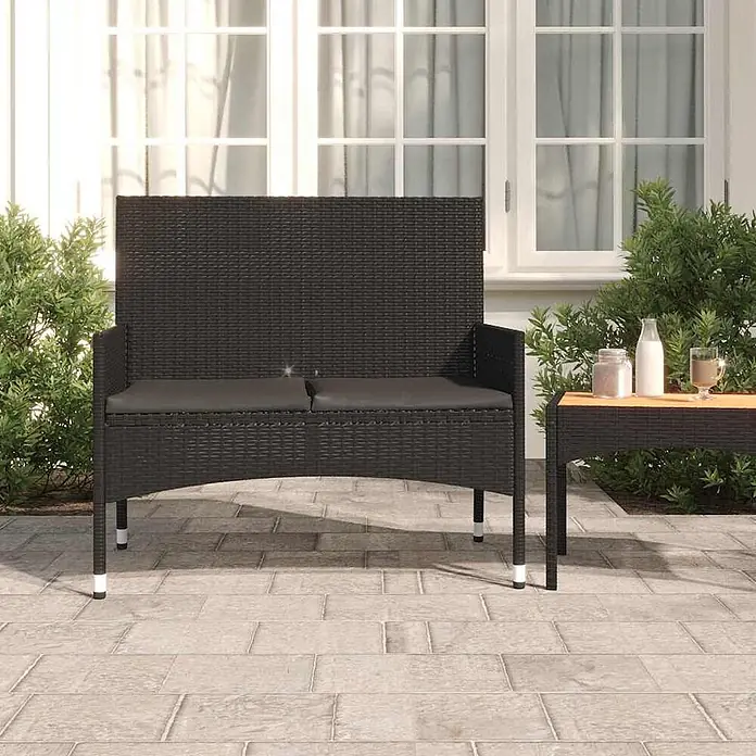 Furnicato Gartenbank - Schwarz - Schwarze Rattan-Gartenbank mit grauen Kissen auf einer Terrasse, neben einem passenden kleinen Tisch.