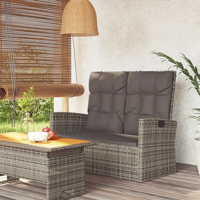 Furnicato Gartenbank - Grau - Grau Rattan Gartensofa und Couchtisch mit anthrazitfarbenen Kissen auf Holzterrasse.