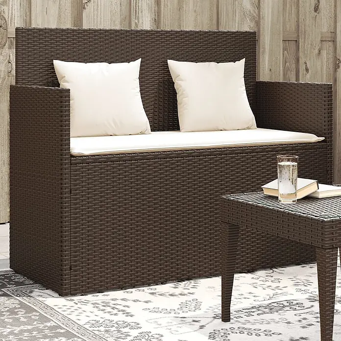 Furnicato Gartenbank PE-Rattan - B x T x H: 120 x 50 x 90,5 cm, Braun - Dunkelbraune Rattan-Gartenbank mit cremefarbenen Kissen und passendem Beistelltisch auf einem gemusterten Teppich.