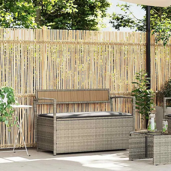 Furnicato Gartenbank PE-Rattan - B x T x H: 111,5 x 54 x 74 cm, Hellgrau und Dunkelgrau - Graue Outdoor-Aufbewahrungsbank aus Polyrattan mit schwarzem Kissen auf einer Terrasse vor Bambuszaun.