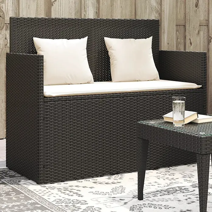 Furnicato Gartenbank PE-Rattan - B x T x H: 120 x 50 x 90,5 cm, Schwarz und Creme - Dunkelbraunes Rattan-Outdoor-Sofa mit cremefarbenen Kissen und passendem Beistelltisch auf einem Outdoor-Teppich.