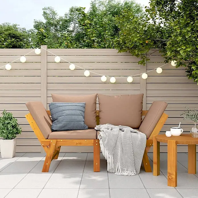 Furnicato Gartenbank Akazien-Massivholz Taupe - B x T x H: 205 x 74 x 66 cm, Taupe - Hölzernes Outdoor-Sofa mit braunen Kissen und passendem Beistelltisch auf einer Terrasse, mit Lichterkette dekoriert.