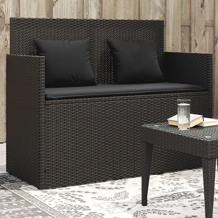 Furnicato Gartenbank - B x T x H: 120 x 50 x 90,5 cm, Schwarz - Dunkelbraune Rattan-Gartenbank mit schwarzen Kissen und passendem Glastisch auf einer Terrasse.