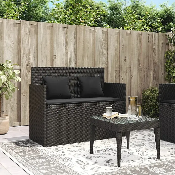 Furnicato Gartenbank PE-Rattan - B x T x H: 120 x 50 x 90,5 cm, Schwarz - Schwarzes Polyrattan-Gartenmöbel-Set mit schwarzen Kissen und Glastisch auf einer Terrasse.