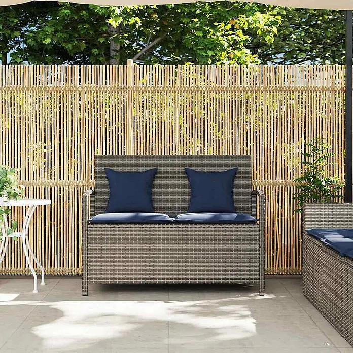 Furnicato Gartenbank PE-Rattan - B x T x H: 111 x 56 x 87 cm, Grau und Marineblau - Graue Rattan-Gartenbank mit blauen Kissen auf einer Terrasse vor einem Bambuszaun.