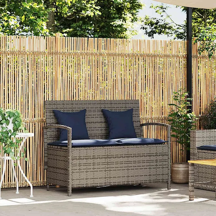 Furnicato Gartenbank PE-Rattan - B x T x H: 111 x 56 x 87 cm, Grau und Marineblau - Graue Rattan-Sitzbank für draußen mit Stauraum, blauen Kissen und Polstern auf einer Terrasse.