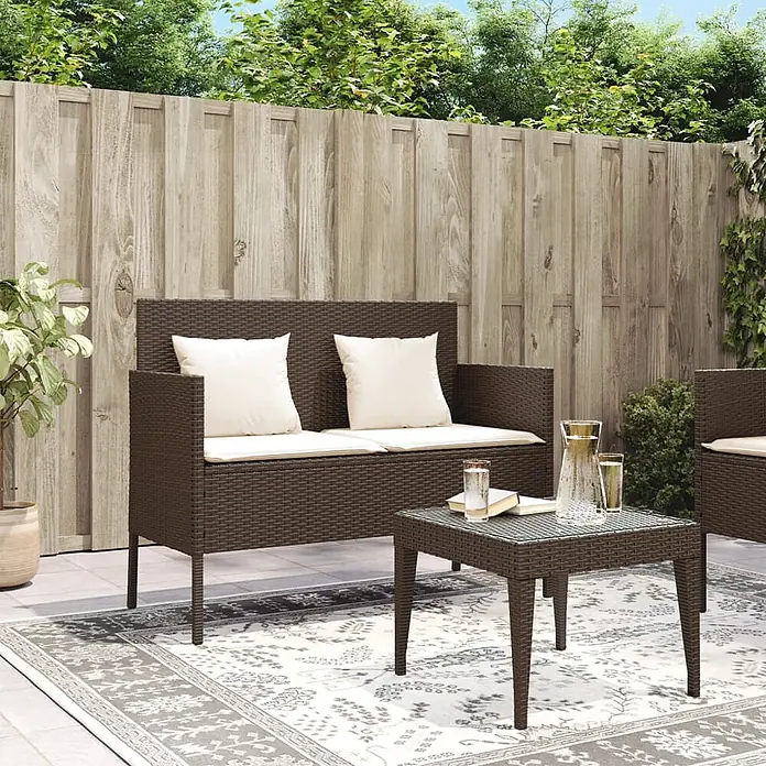 Furnicato Gartenbank PE-Rattan - B x T x H: 113 x 61 x 87 cm, Braun - Braunes Rattan-Outdoor-Sofa für zwei Personen mit hellen Kissen und passendem Couchtisch auf einem gemusterten Teppich.