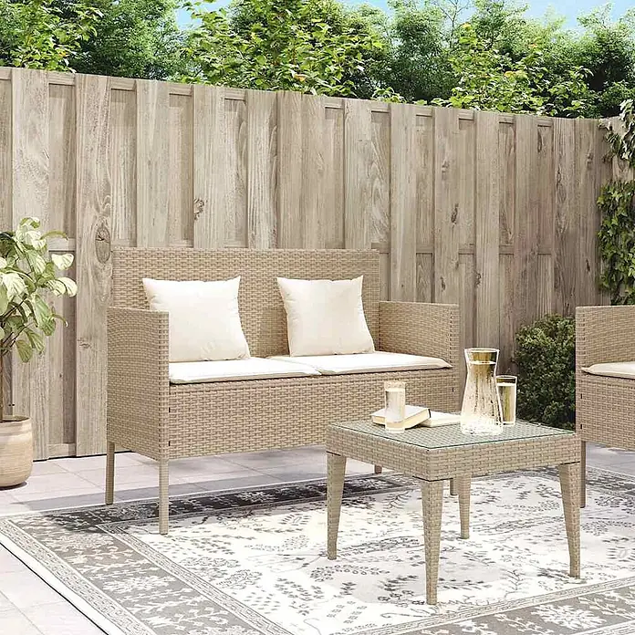 Furnicato Gartenbank PE-Rattan - B x T x H: 113 x 61 x 87 cm, Beige und Creme - Beiges Outdoor-Sofa und Couchtisch in Rattan-Optik mit cremefarbenen Kissen auf einem Terrassenteppich.