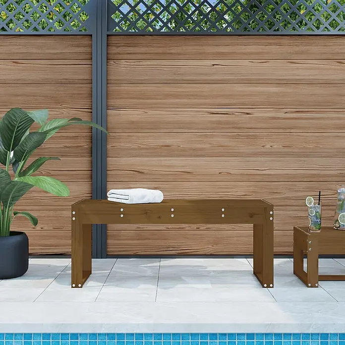Furnicato Gartenbank Kiefernholz Honigbraun - B x T x H: 110 x 38 x 45 cm, Honigbraune Kiefer - Braune Holzgartenbank und kleiner Tisch am Pool, mit Handtuch und Getränken.