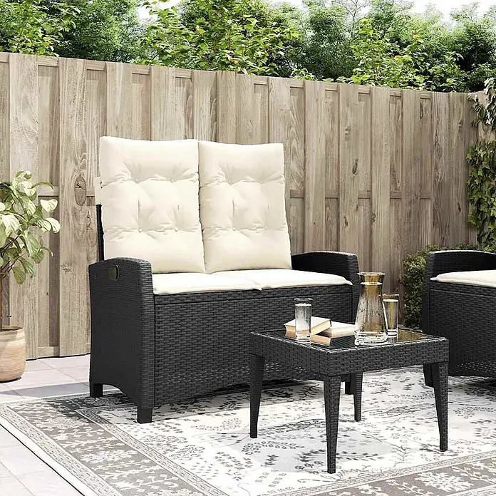 Furnicato Gartenbank - B x T x H: 66 x 90 x 93 cm, Schwarz und Creme - Schwarzes Rattan-Gartensofa mit cremefarbenen Kissen und passendem Couchtisch auf einer Terrasse.